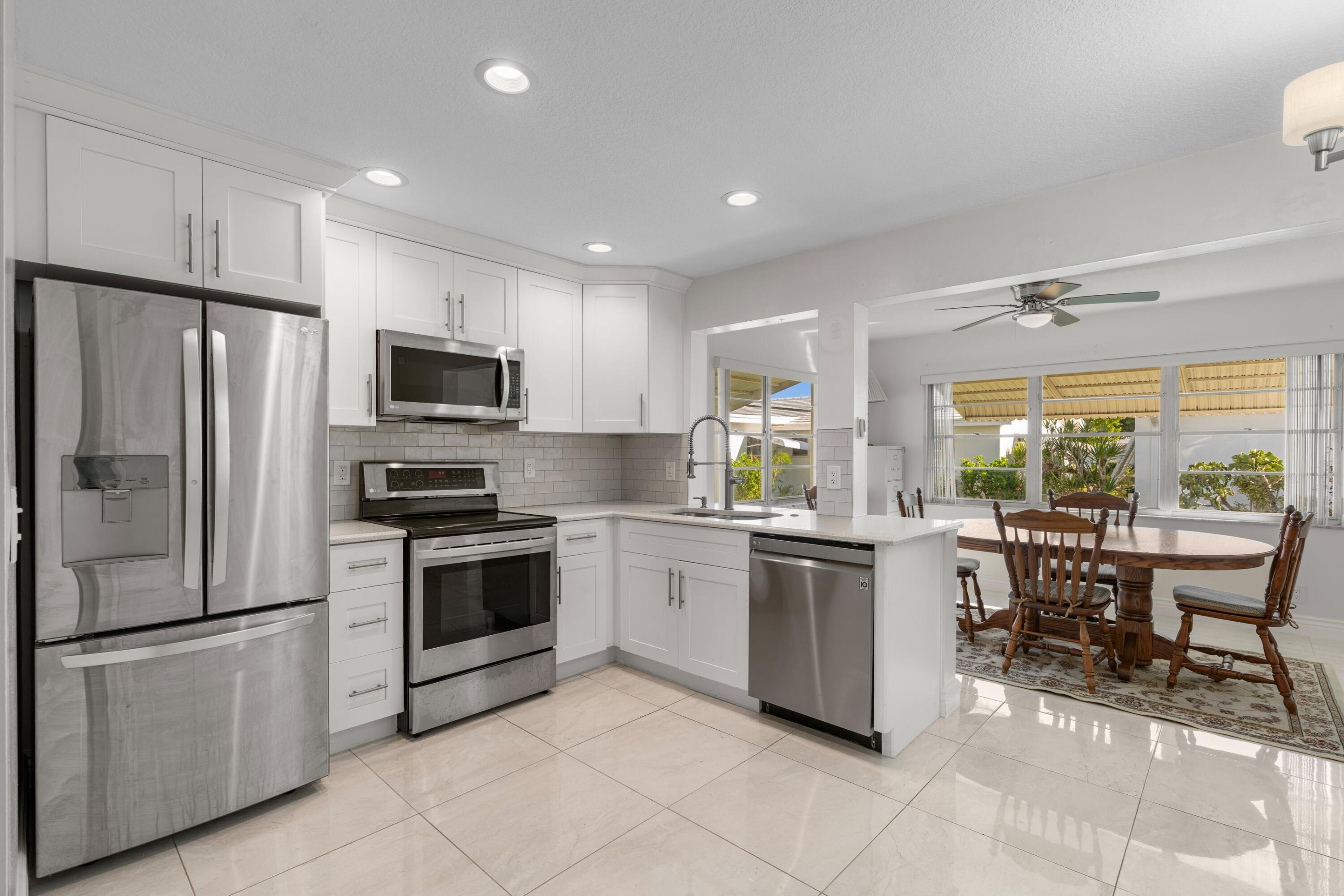 816 Southwest 18th Court Boynton Beach, FL 33426 - Photo 4 of 37 a kitchen with stainless steel appliances granite countertop a refrigerator a stove top oven a sink dishwasher a dining table and chairs with wooden floor