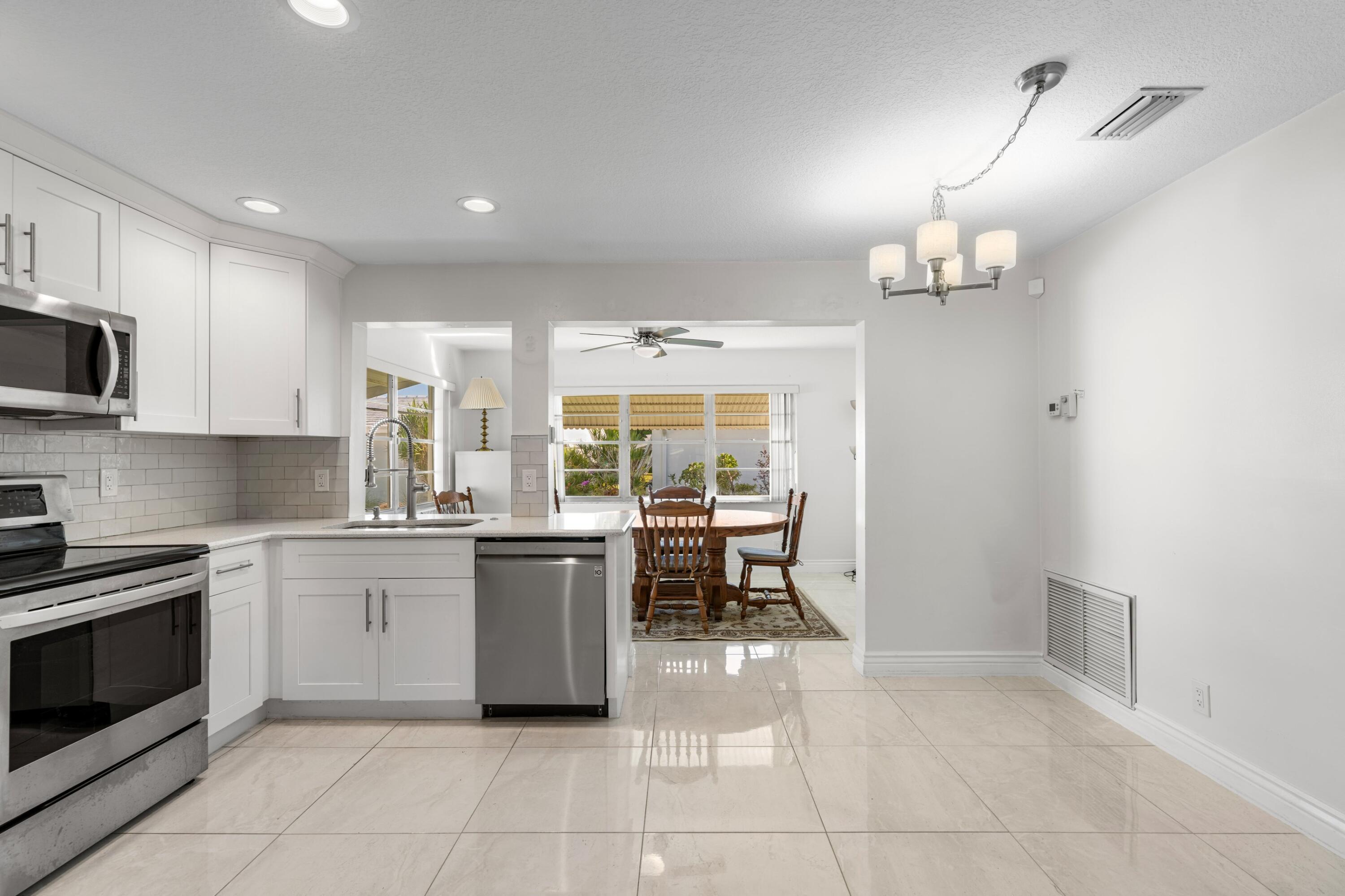 816 Southwest 18th Court Boynton Beach, FL 33426 - Photo 7 of 37 a kitchen with stainless steel appliances a stove a sink a oven a dining table and chairs