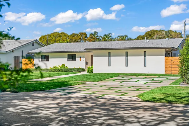 a living room with stainless steel appliances furniture wooden floor and a kitchen view