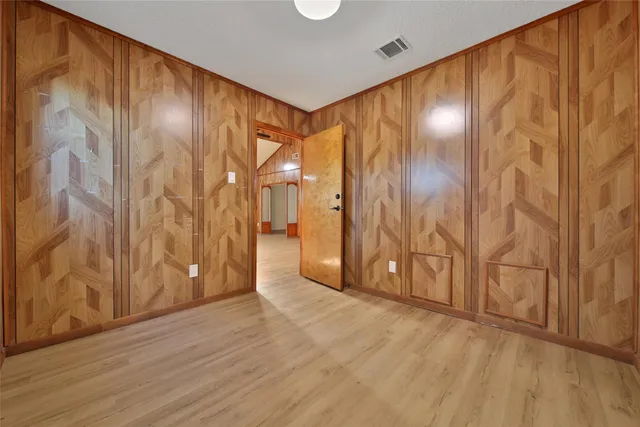 an empty room with a fan and a chandelier fan