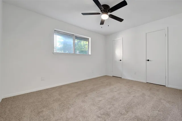 en empty room with ceiling fan and window