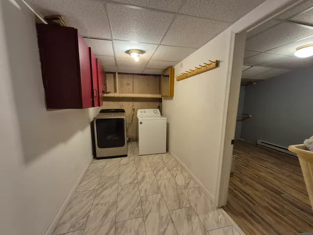 a view of a refrigerator in kitchen and an empty room with wooden floor