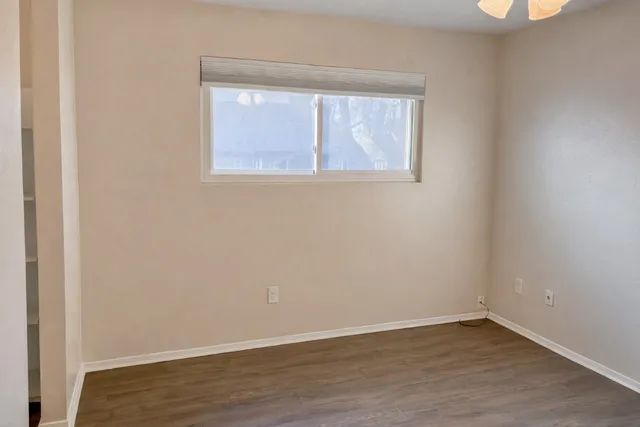 an empty room with wooden floor and windows