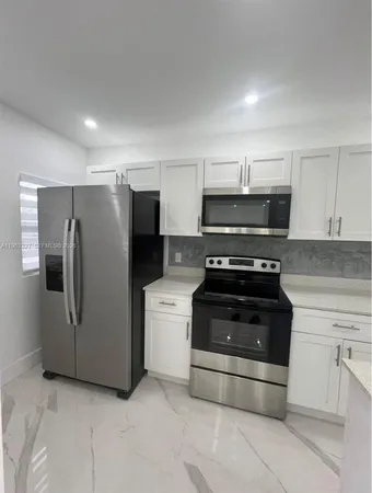 a kitchen with granite countertop a refrigerator and a stove top oven