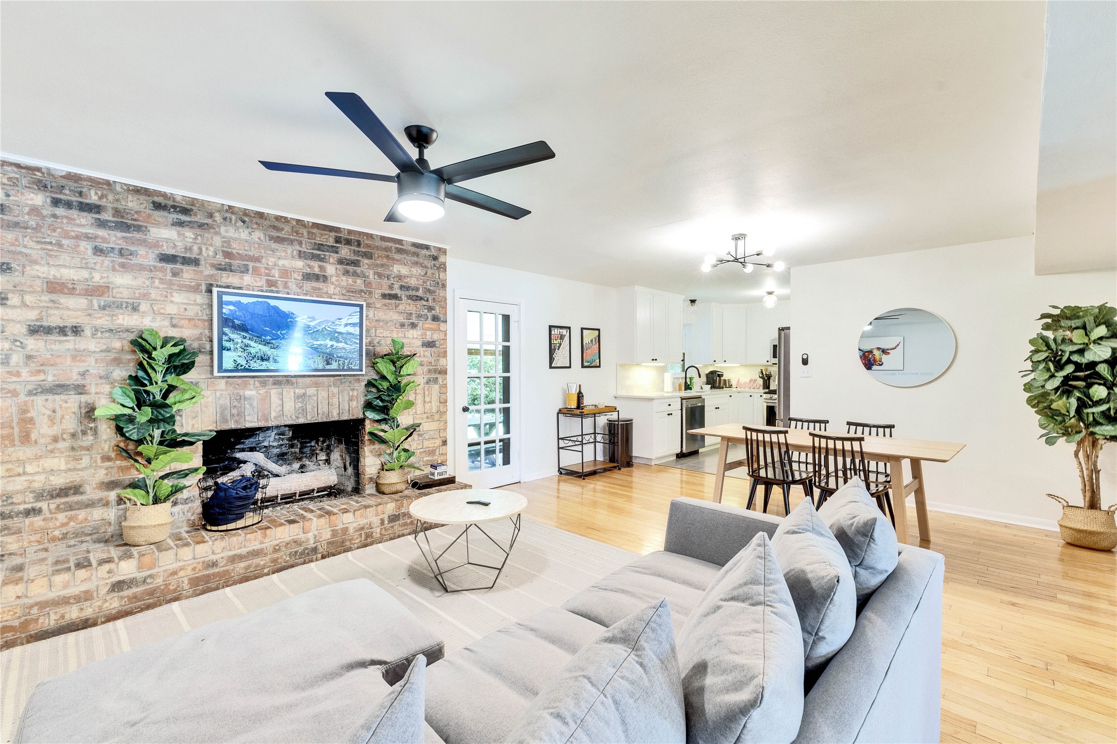 3306 South Pleasant Valley Road Austin, TX 78741 - Photo 1 of 1 Living room with a fireplace, light wood-type flooring, a ceiling fan, and brick wall