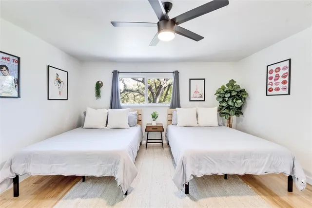 a spacious bedroom with a bed painting on wall and two windows