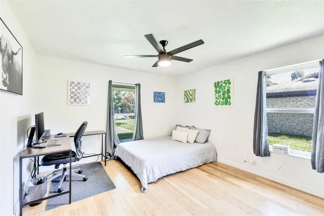 a bedroom with a bed a desk and chair with window