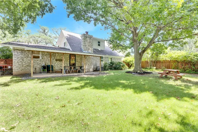 a view of a house with a big yard and large tree
