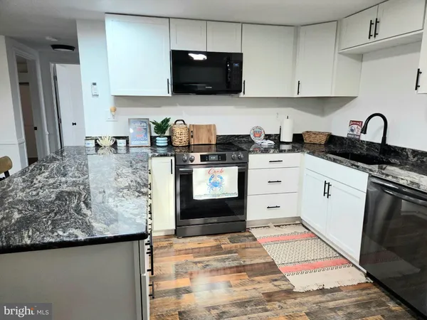 a kitchen with stainless steel appliances granite countertop a stove a sink and a white cabinets