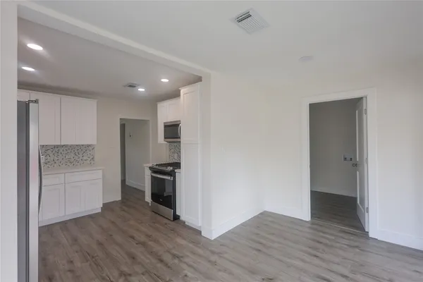 a view of kitchen view wooden floor and stainless steel appliances