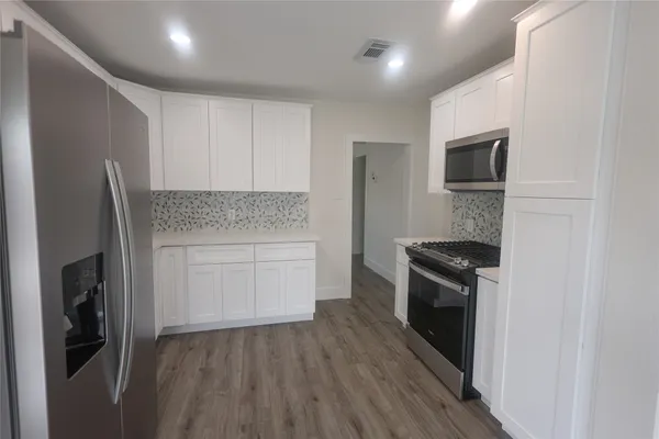 a kitchen with granite countertop a refrigerator stove and microwave