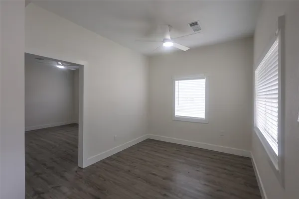 an empty room with wooden floor and windows