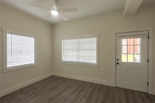 an empty room with wooden floor and windows