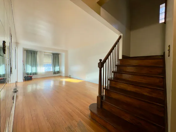 a view of a hallway with wooden floor and a bathroom