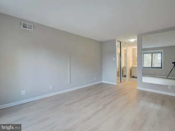 a view of an empty room with window and wooden floor