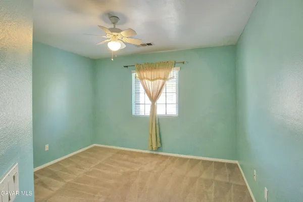 an empty room with a window and a fan