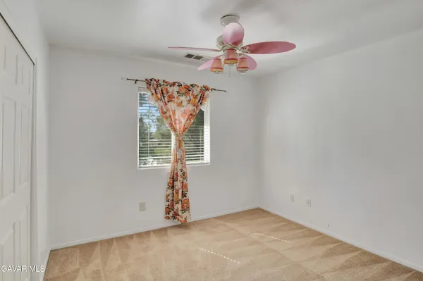 an empty room with a chandelier fan and windows