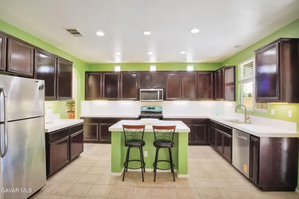 a kitchen with stainless steel appliances granite countertop a sink counter space and chairs