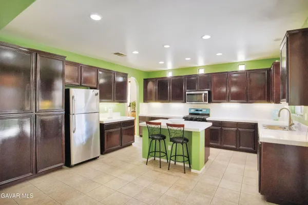 a kitchen with stainless steel appliances kitchen island granite countertop a sink and a refrigerator