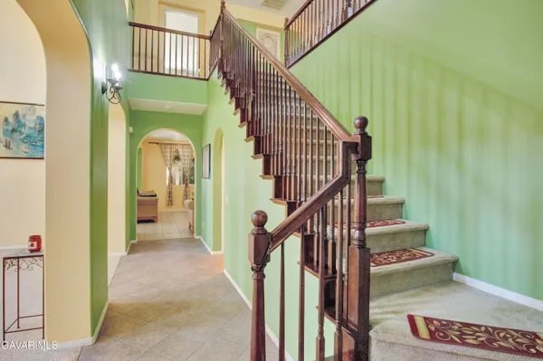 a view of staircase with railing and a chandelier