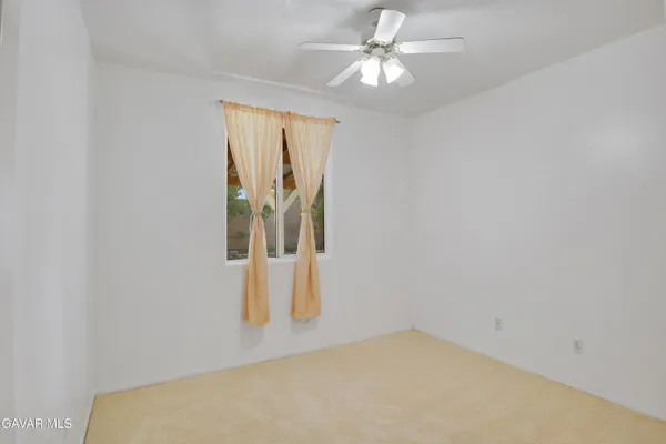 an empty room with a window and a ceiling fan