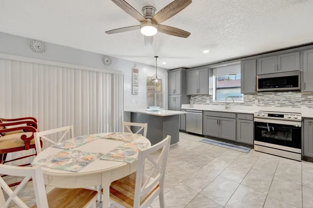 a kitchen with a stove a sink a microwave a dining table and chairs