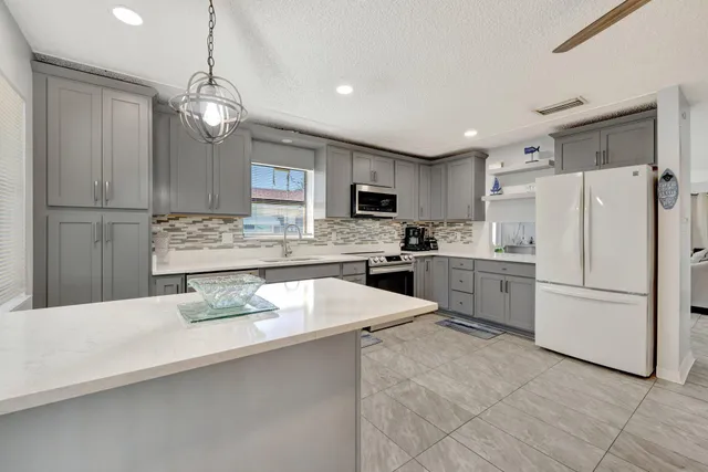 a kitchen with a refrigerator a stove a sink and white cabinets