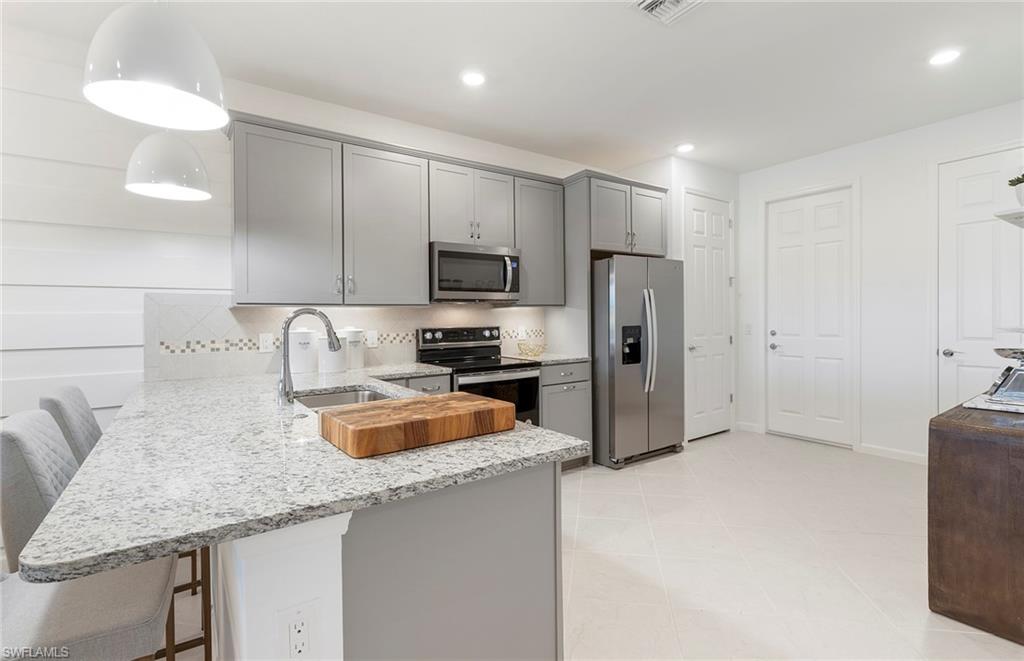 6426 Memorial Lane Ave Maria, FL 34142 - Photo 16 of 38 a kitchen with granite countertop a refrigerator a sink a stove a microwave and island
