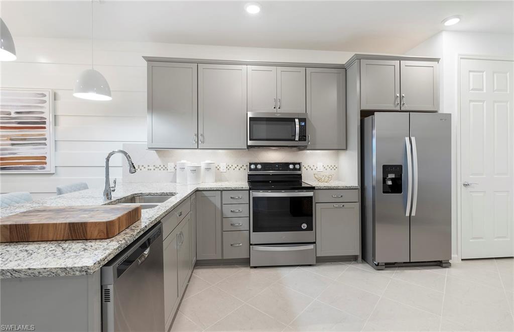 6426 Memorial Lane Ave Maria, FL 34142 - Photo 17 of 38 a kitchen with granite countertop a sink stove and refrigerator