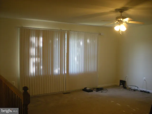 an empty room with windows and chandelier fan