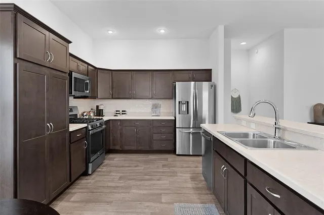 a kitchen with stainless steel appliances granite countertop a refrigerator a sink dishwasher a stove top oven a sink and dishwasher