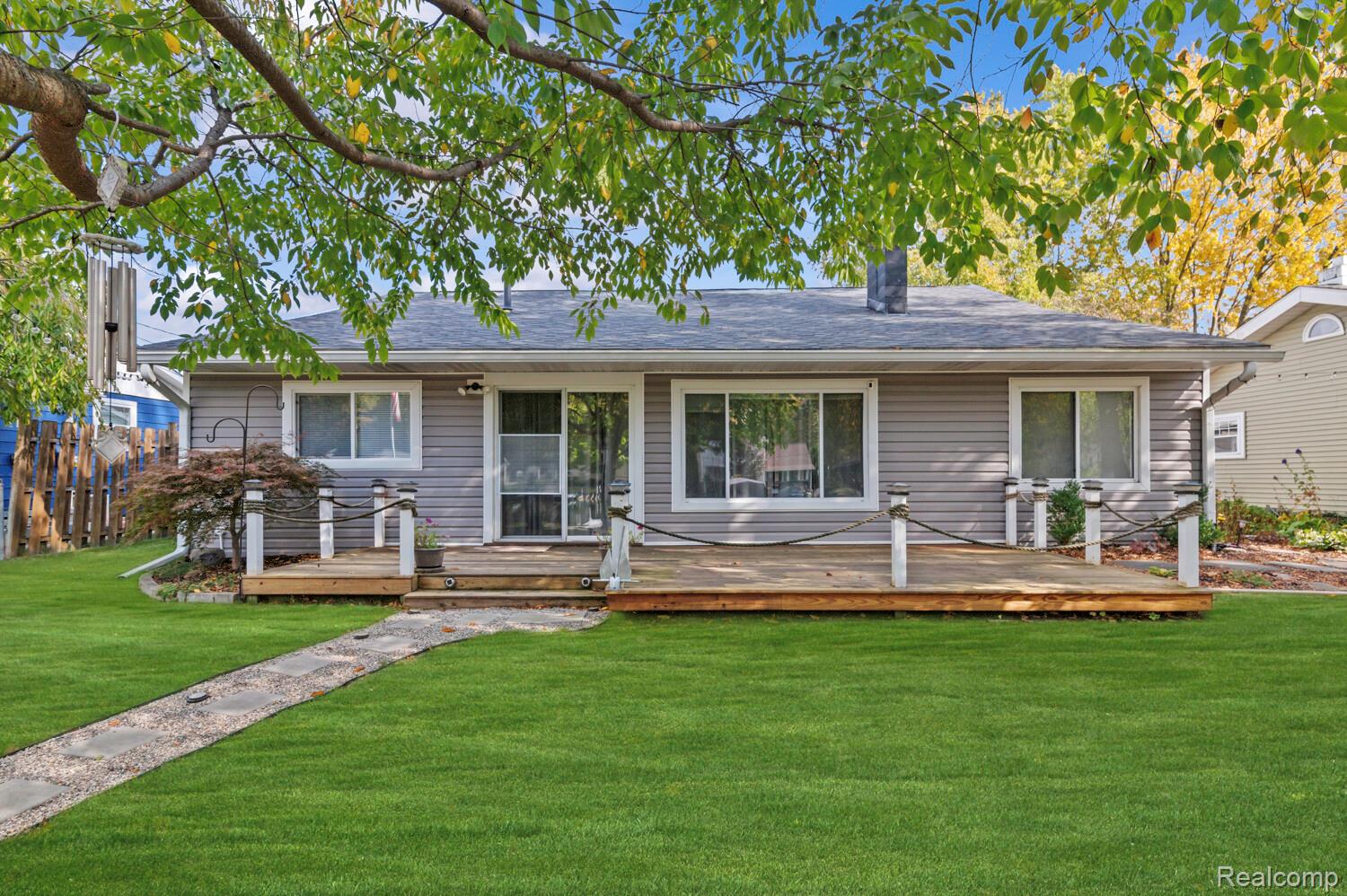11026 Colony Pinckney, MI 48169 - Photo 33 of 40 View of front of home featuring a front yard, a wooden deck, a chimney, and a shingled roof