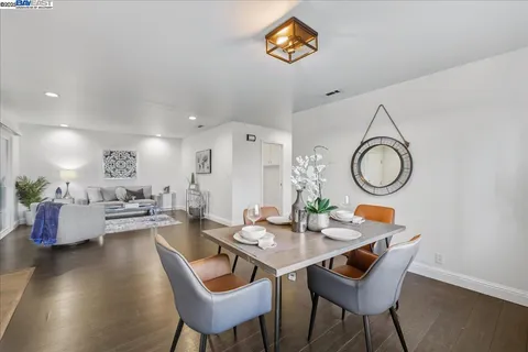 a dining room with wooden floor a chandelier a wooden table and chairs