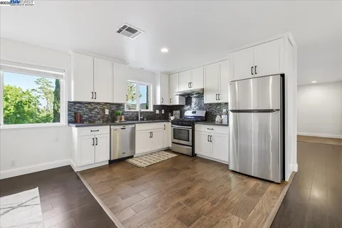 a kitchen with white cabinets white stainless steel appliances and refrigerator