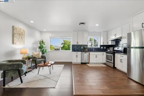 a kitchen with granite countertop a refrigerator oven a sink dishwasher a dining table and chairs with wooden floor