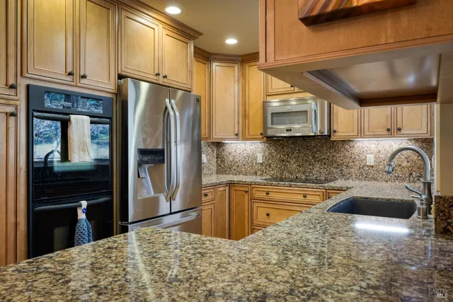 a kitchen with stainless steel appliances granite countertop a refrigerator a stove a sink and dishwasher