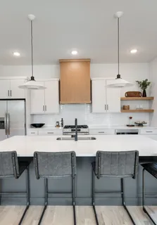 a kitchen with a stove a sink a counter top space a dining table and chairs