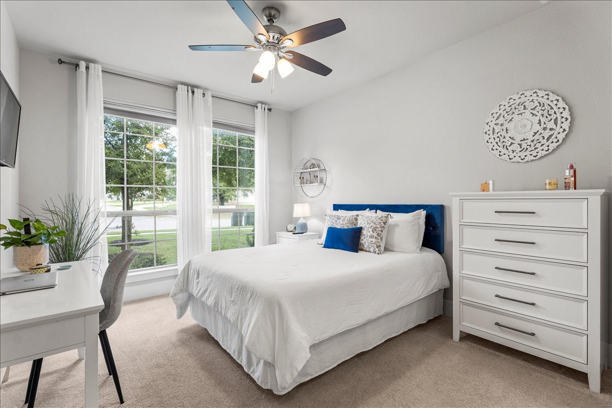 200 Draco Street Georgetown, TX 78628 - Photo 17 of 39 a bedroom with a large bed and a chandelier