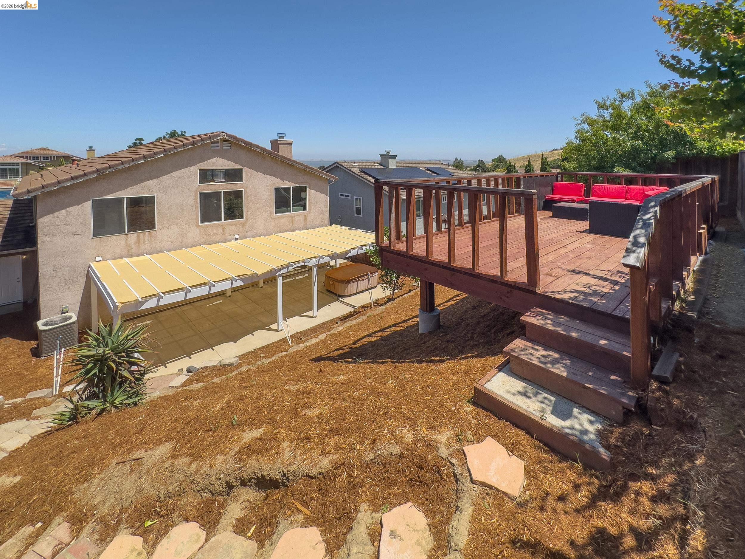 512 Burdick Drive Bay Point, CA 94565 - Photo 43 of 50 Multi-level exterior featuring a ground-level patio with a retractable awning, a raised wooden deck with railings and steps, and a spa