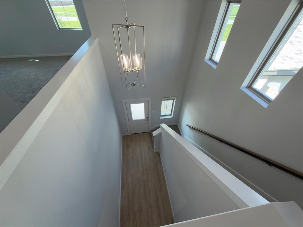 120 Millwood Road Lavon, TX 75166 - Photo 10 of 34 Grand entryway featuring high ceilings, wood-finish flooring, a contemporary chandelier, multiple transom windows, and a frosted glass front door