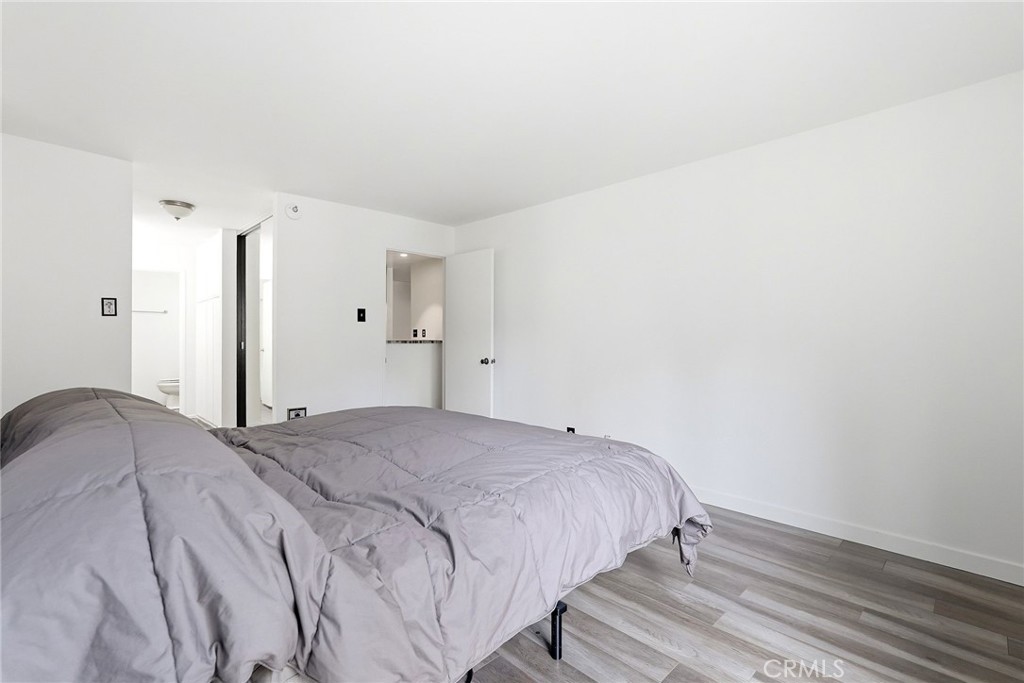 7890 East Spring Street, Unit 11E Long Beach, CA 90815 - Photo 34 of 40 a bedroom with a bed and wooden floor