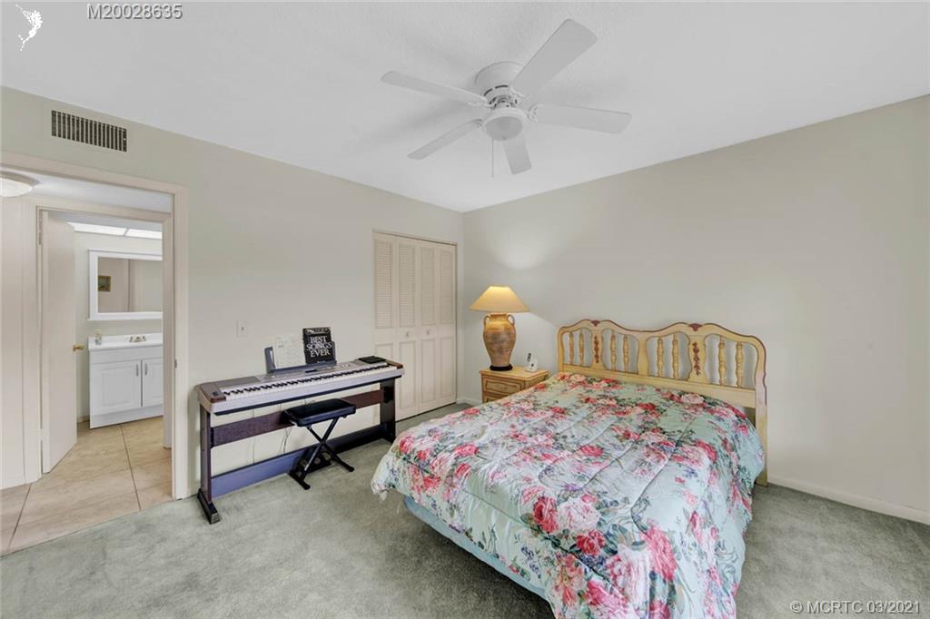 1860 Southwest Palm City Road, Unit 201 Stuart, FL 34994 - Photo 30 of 45 a bedroom with a bed and a chandelier