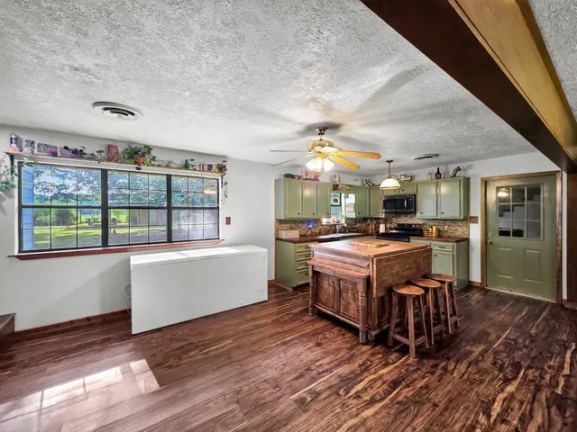 a large kitchen with stainless steel appliances a large counter top a stove and a wooden floors