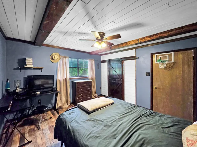 a bedroom with a bed dresser and a large window