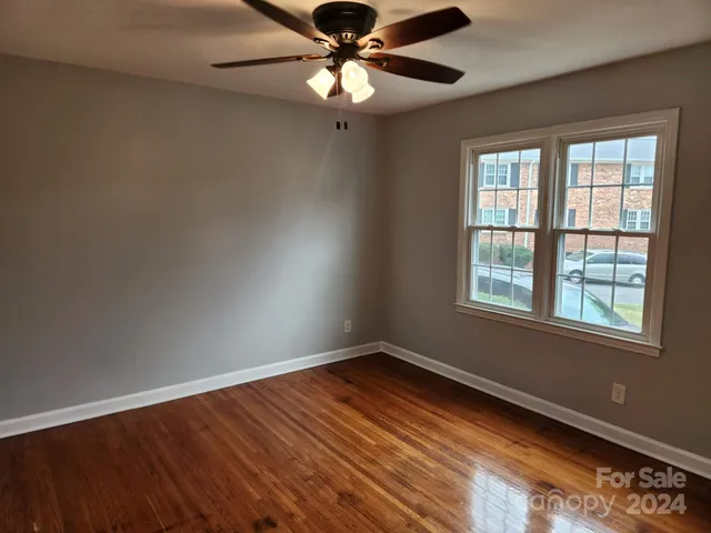 a view of an empty room with window and chandelier fan