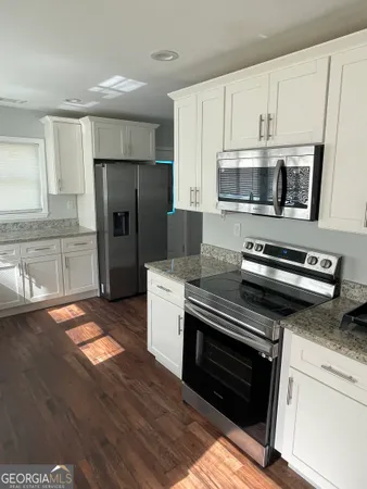 a kitchen with granite countertop a refrigerator stove and microwave