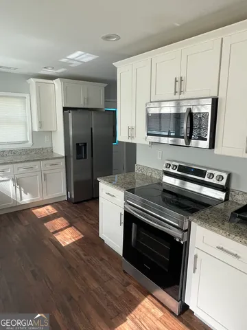 a kitchen with granite countertop a refrigerator stove and microwave
