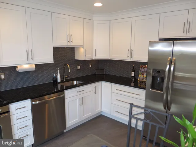 a kitchen with granite countertop white cabinets and black appliances