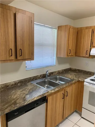 a kitchen with granite countertop a sink a stove and cabinets