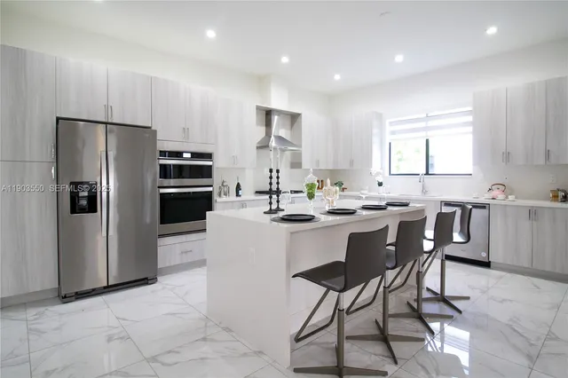 a kitchen with stainless steel appliances granite countertop a refrigerator a sink a stove a dining table and chairs